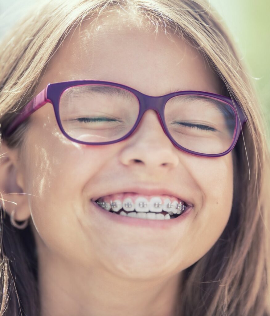 Young girl with glasses and orthodontic braces laughing outdoors — Cornerstone Dental Arts smile gallery Knoxville TN