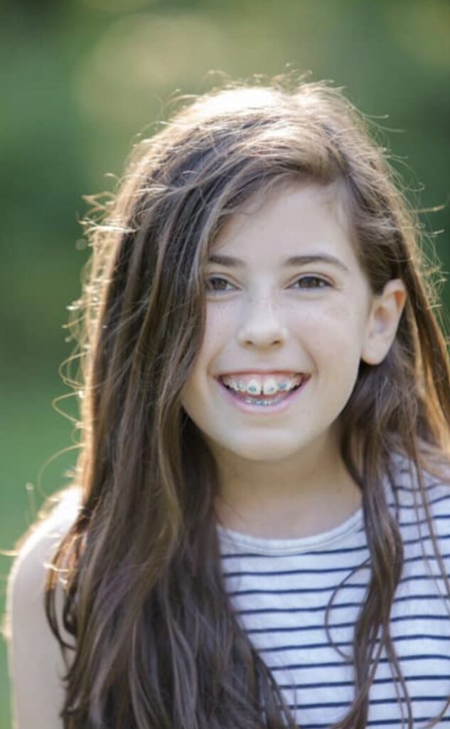 Teen girl with long hair and orthodontic braces smiling naturally outdoors — Cornerstone Dental Arts smile gallery Knoxville TN
