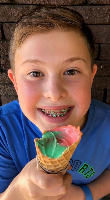Young boy with colorful orthodontic braces smiling while holding an ice cream cone — Cornerstone Dental Arts smile gallery Knoxville TN