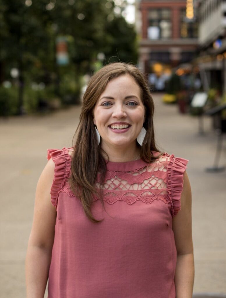 Young woman in pink top smiling naturally on a downtown street — Cornerstone Dental Arts smile gallery Knoxville TN