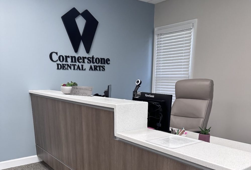 Cornerstone Dental Arts reception desk with W logo backdrop in the Knoxville, TN office.