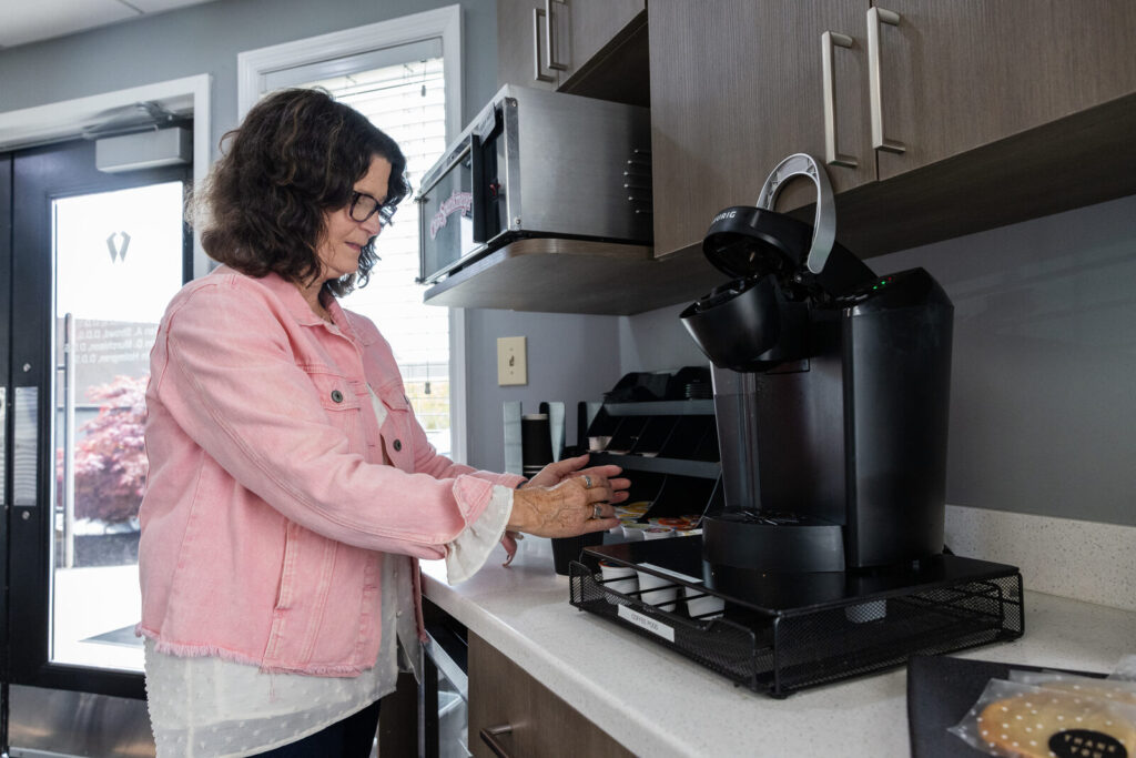 A patient pouring complimentary coffee at the Cornerstone Dental Arts refreshment station in Knoxville, TN
